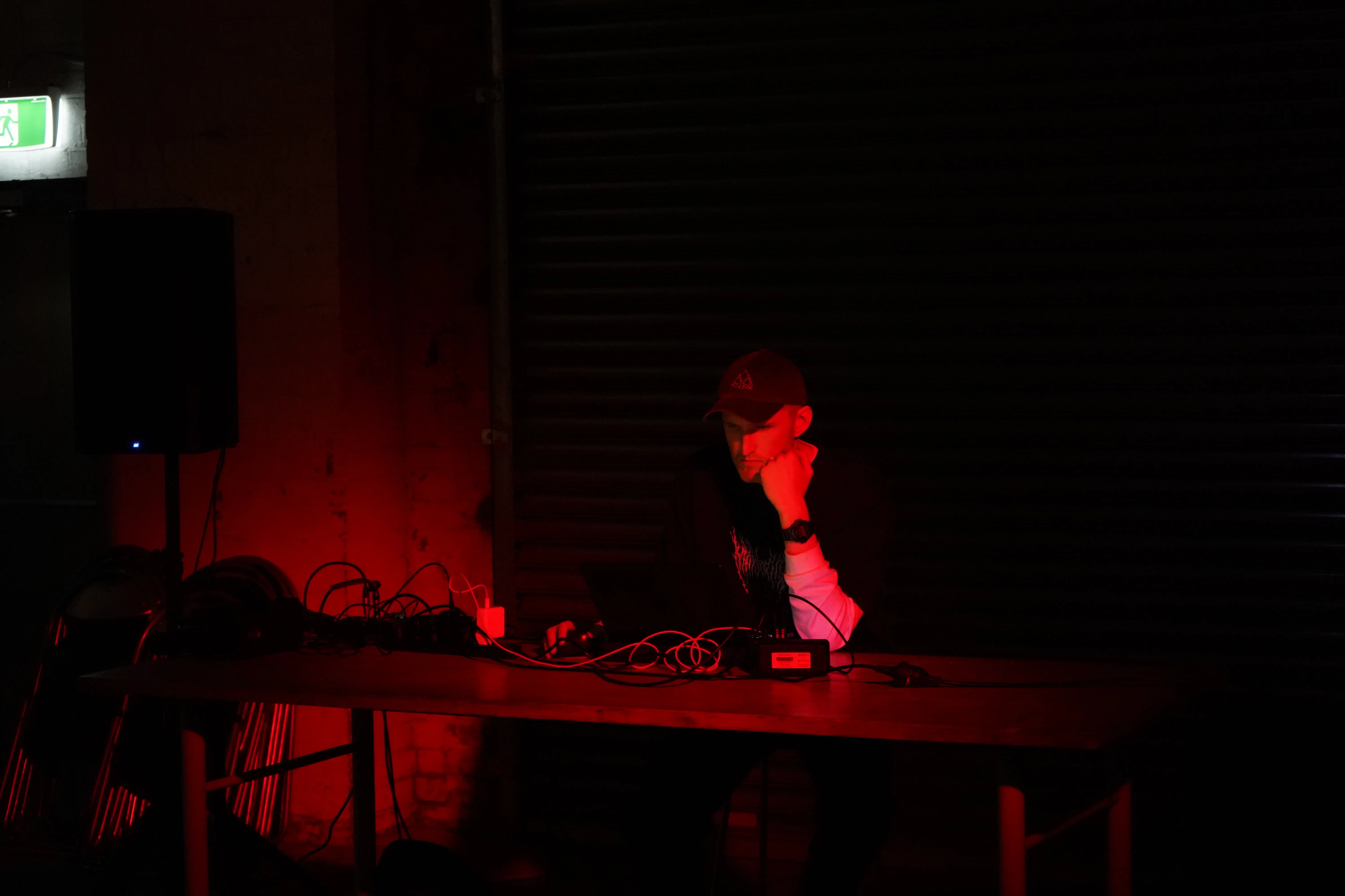 James Bradbury performing live, seated at a mixing desk under red light